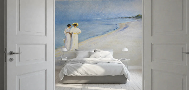 "Summer Evening on the Southern Beach" by Peder Severin Krøyer, made as a large wallpaper mural, shown installed in a bedroom above a bed with white bedding and flanked by open white paneled doors.