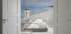 A large wall mural depicting "Summer Evening on the Southern Beach" by Peder Severin Krøyer, made as a large wallpaper mural. Featuring a beach scene with two figures in white robes, shown installed in a bedroom above a bed with white bedding and flanked by open white paneled doors.