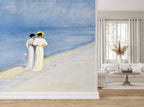 "Summer Evening on the Southern Beach" by Peder Severin Krøyer, made as a large wallpaper mural featuring an impressionist painting of two women in white dresses standing on a blue beach, shown installed in a modern living room next to a white sofa and window.