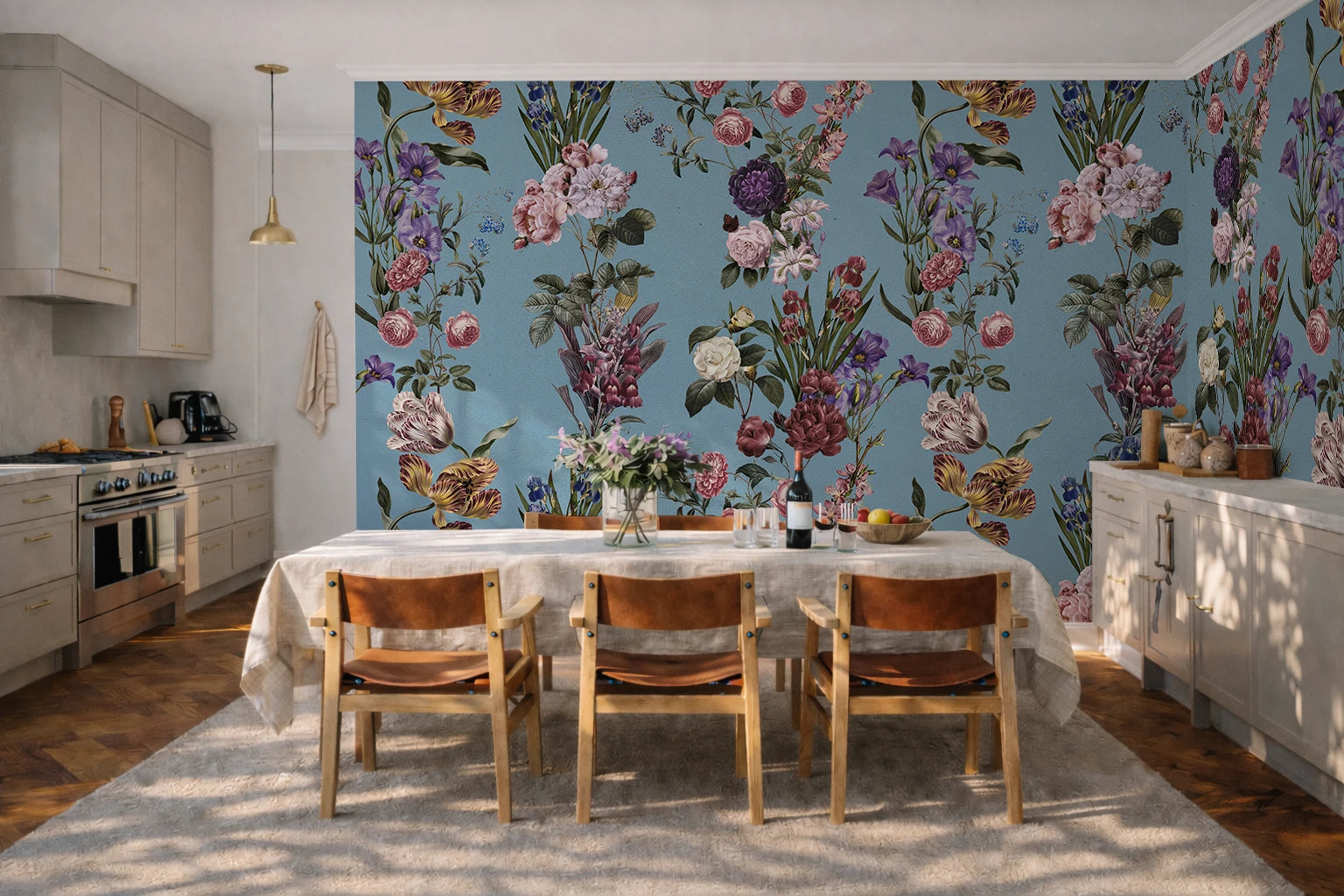 A dining room interior featuring a large floral wallpaper mural on the back wall and side wall, with a table, chairs, and kitchen cabinetry visible in a sunlit room.