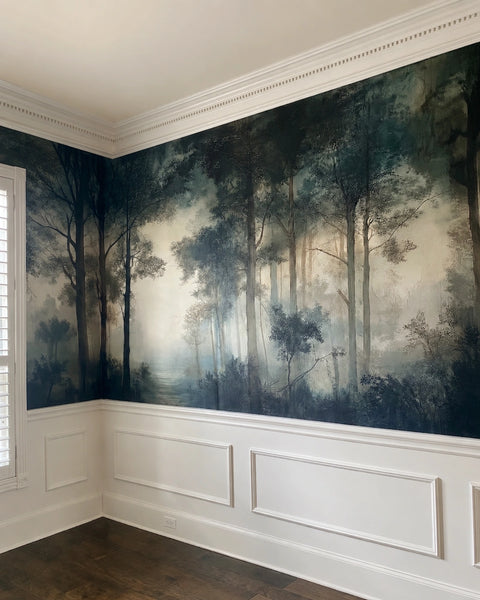 Room with moody forest wallpaper mural on the wall and white wainscoting.