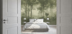 A bedroom interior with a large wallpaper mural showing a misty green forest scene behind a neatly made bed with white bedding. White doors frame the left and right sides of the view.
