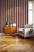 Living room with striped red wallpaper, wooden floor, and furniture.