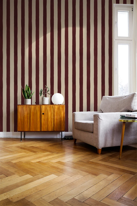 Living room with striped red wallpaper, wooden floor, and furniture.