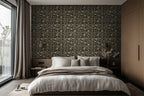 A luxurious bedroom with the walls adorned with a geometric and palm tree patterned wallpaper in deep noir black with luminous gold detailing. The room features a large bed, wooden flooring, large windows.