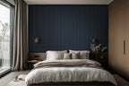 Modern bedroom with white pillows and duvet, wooden details, and a wallpaper with gold and navy blue stripes.  