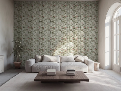 A living room with large windows, featuring a wall covered in floral wallpaper with a geometric trellis design, a white sofa, and a wooden coffee table.