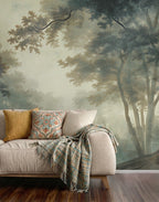 Sofa with decorative pillows and a blanket against a forest wallpaper mural.