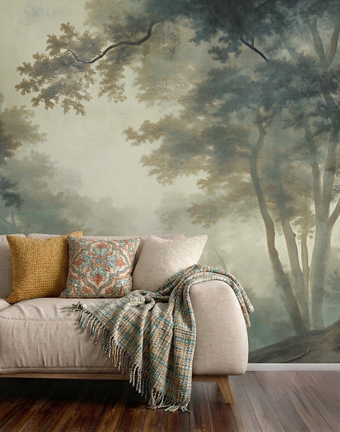 Sofa with decorative pillows and a blanket against a forest wallpaper mural.