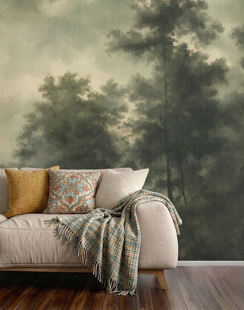 Sofa with decorative pillows and a blanket against a painted forest mural wallpaper.