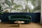 Modern living room with a green sofa, wooden coffee table, and tropical leaf wallpaper.