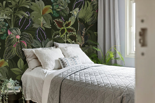 Bedroom with a bed against a wall featuring tropical leaf and flower wallpaper.