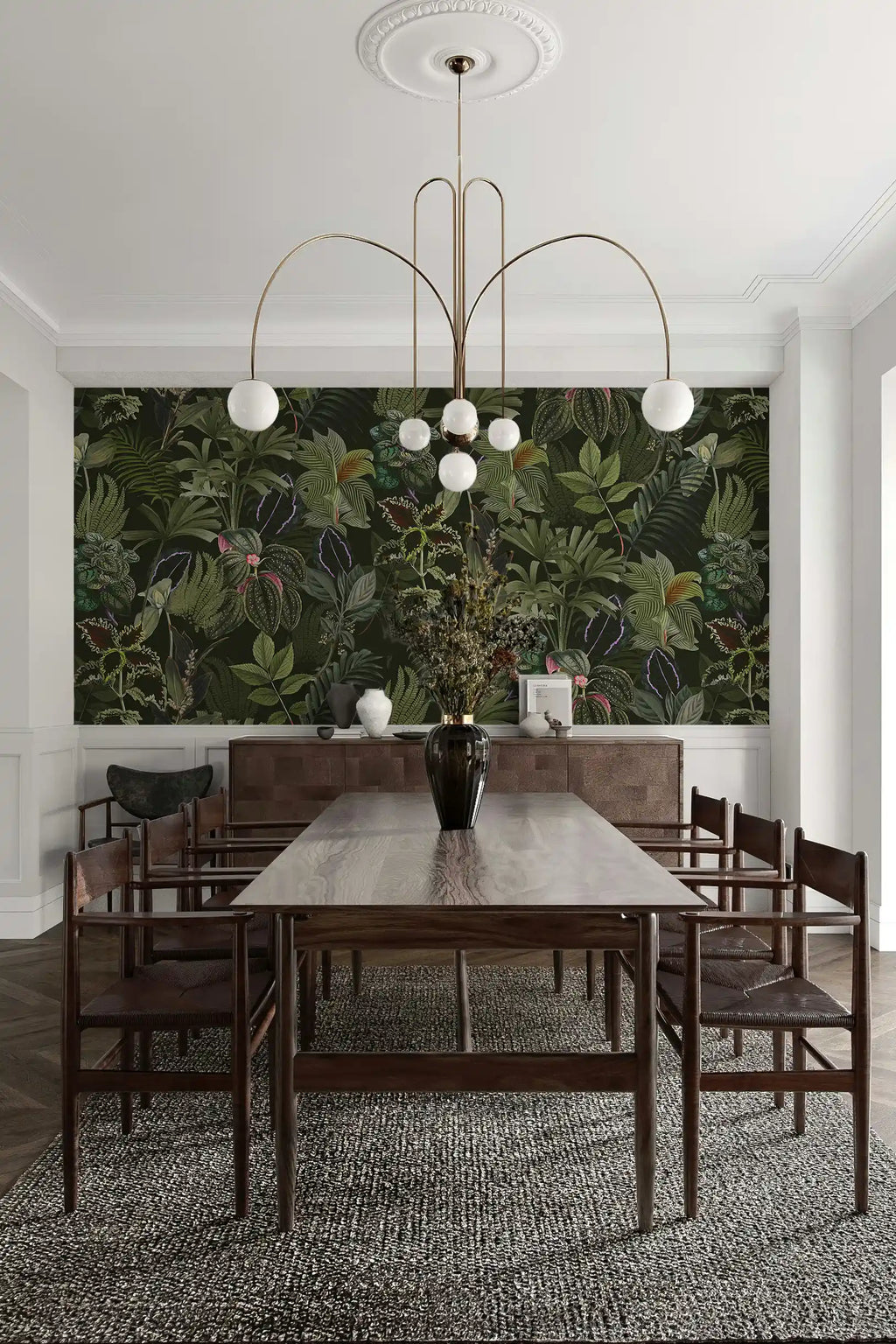 Dining room with a long wooden table and chairs, featuring a large wallpaper mural of green foliage.