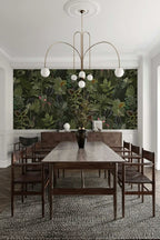 Dining room with a long wooden table and chairs, featuring a large wallpaper mural of green foliage.