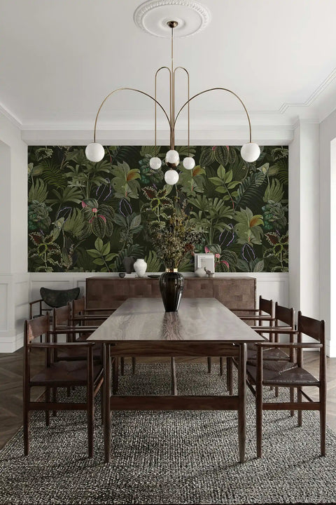 Dining room with a long wooden table and chairs, featuring a large wallpaper mural of green foliage.