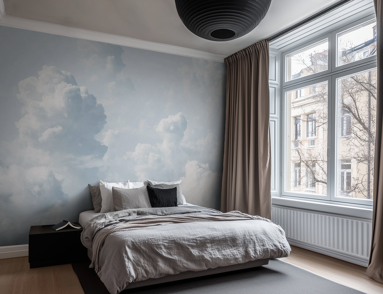 A bedroom with a large window, a bed, and a wall covered in a white cloud-patterned wallpaper.