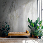 A modern lounge area with a barcelona daybed in brown, plants, and marble wallpaper