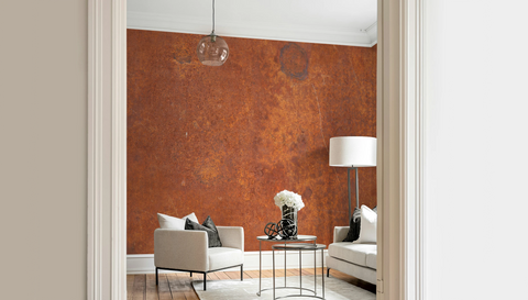 Modern living room with a white arm chair, and a wallpaper mural with industrial rust texture. 