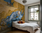 Modern bedroom wth a bed, white sheets, and a large wallpaper mural of Van Gogh's "The Siesta"