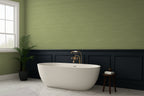 Modern bathroom with a freestanding bathtub against a green wall with green grasscloth wallpaper