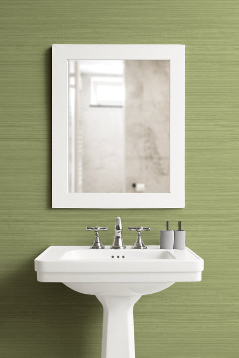 Bathroom setup with a white pedestal sink and mirror against a green wall with green grasscloth wallpaper