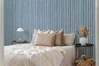 Bedroom with blue striped wallpaper, bed with beige pillows, and side tables.