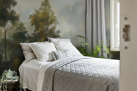 Bedroom with a bed covered in white bedding, surrounded by decorative elements. Large wallpaper vintage forest mural on the wall. 