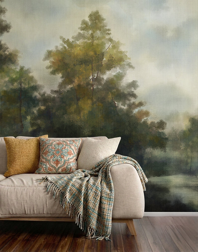 Sofa with decorative pillows and a blanket against a wallpaper forest mural.