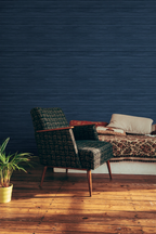 A modern lounge living room with a retro armchair and blue grasscloth wallpaper. 