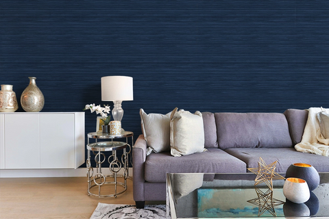 A modern maximalist living room with a blue sofa and navy blue faux grasscloth wallpaper with a rich woven texture. 