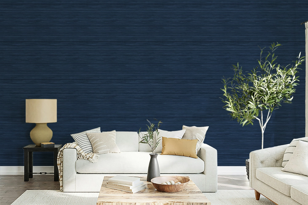 A modern maximalist living room with a beige sofa, olive tree, a and navy blue faux grasscloth wallpaper with a rich woven texture. 