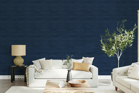 A modern maximalist living room with a beige sofa, olive tree, a and navy blue faux grasscloth wallpaper with a rich woven texture. 