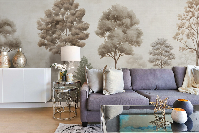 Modern living room with a blue sofa, accent table, sofa table, and vintage forest mural wallpaper