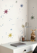 Kids galaxy space wallpaper above a desk with a laptop and lamp.