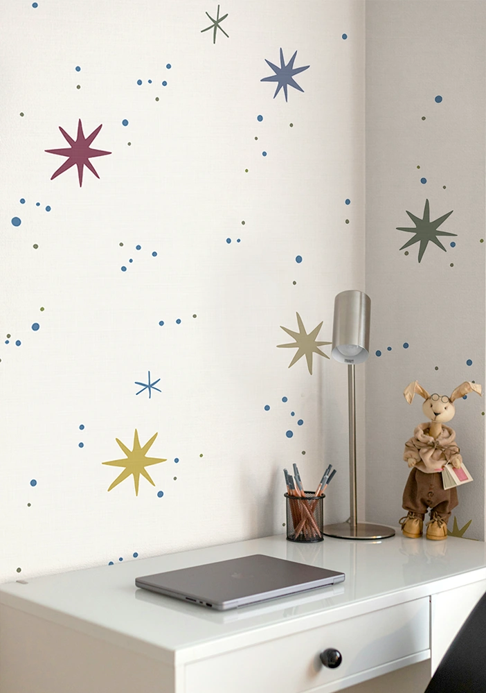 Kids galaxy space wallpaper above a desk with a laptop and lamp.