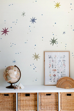 Kids room, a wall with star and planet wallpaper, framed poster, globe, and wicker baskets.