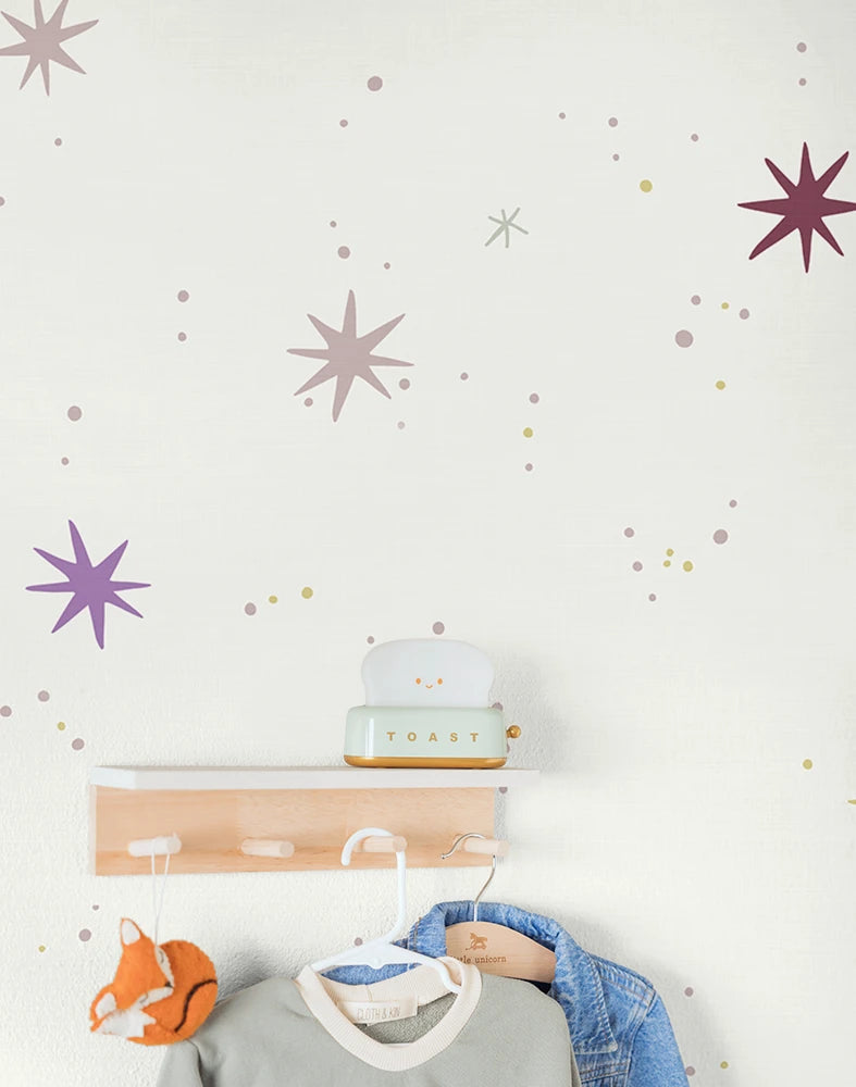 Kids star wallpaper and a coat rack with clothes and a toy on a light background