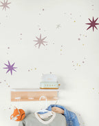 Kids star wallpaper and a coat rack with clothes and a toy on a light background