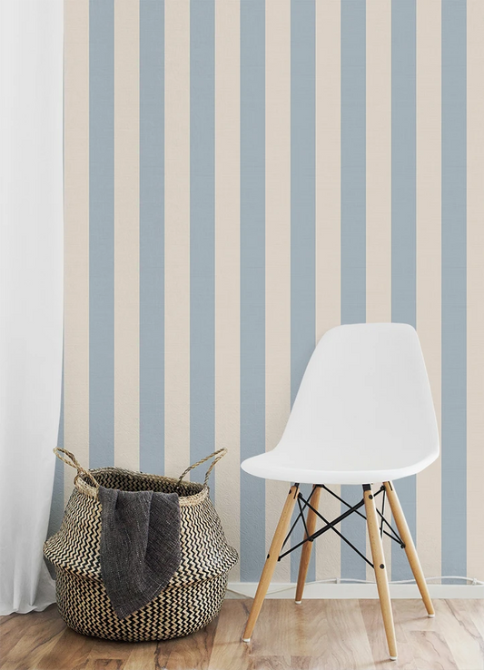 Kids room with a white chair and woven basket against a striped kids wallpaper.