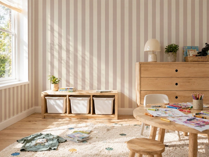 Children's playroom with wooden furniture, toys, and striped pink kids wallpaper.