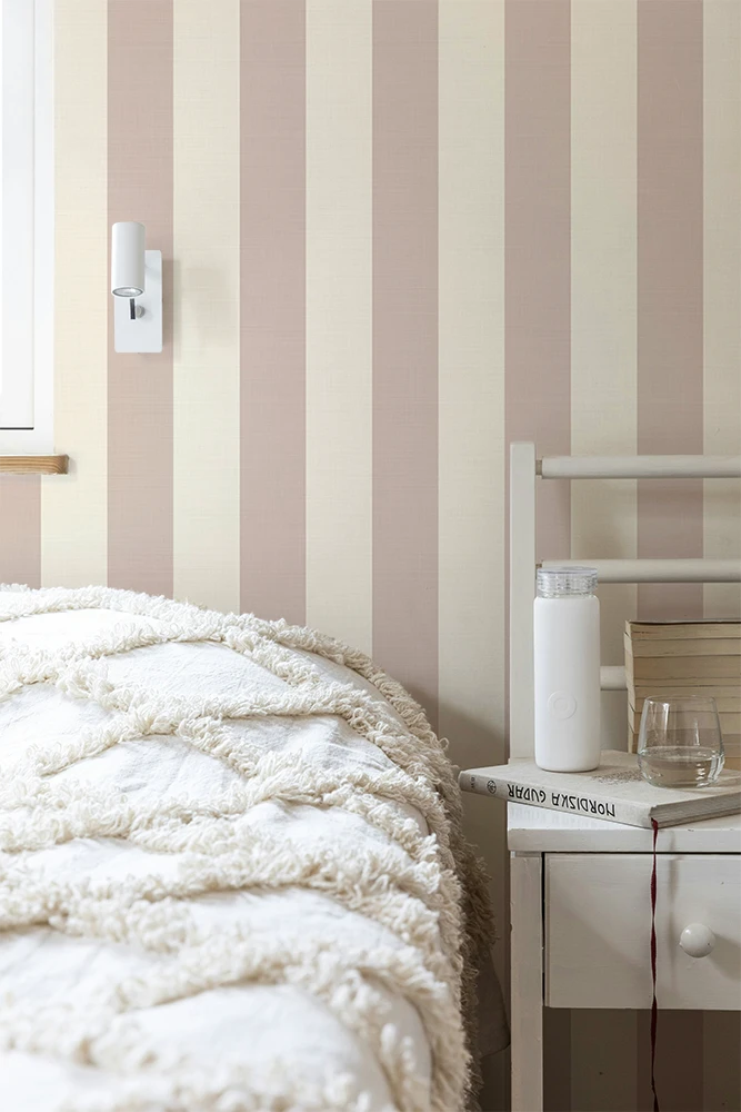 Teenager bedroom with striped wallpaper, white bedding, and a nightstand.