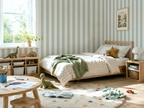 Children's bedroom with striped wallpaper, bed, and toys.