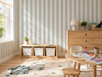 Children's playroom with wooden furniture, toys, and subtle striped wallpaper.