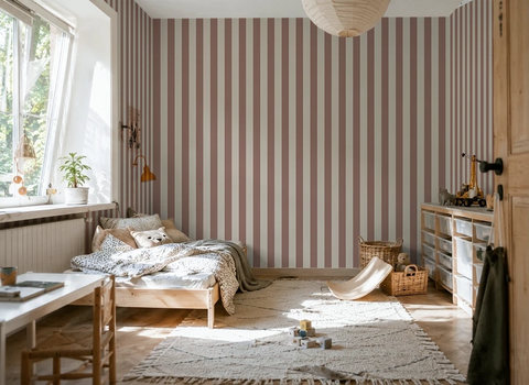 Kids room with striped terracotta kids wallpaper, wooden crib, and toys on a rug.