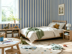 Children's bedroom with striped wallpaper, bed, and toys on a rug.