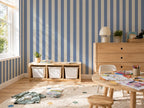 Children's room with blue and white striped wallpaper, wooden furniture, and toys on the floor.
