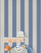 Wall with blue and beige striped wallpaper featuring a shelf and hanging kid's clothes.