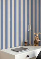 Desk with laptop, lamp, and decorative items against a wall with striped blue and white wallpaper. 