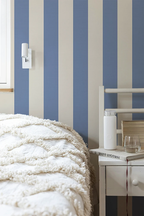 Room interior with blue and white striped wallpaper, bed, and desk.