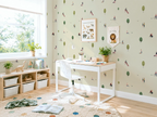 Children's room with a desk, books, and decorative elements on a wall with park-themed wallpaper.